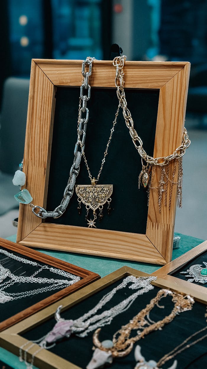 services-02 Various necklaces elegantly displayed in a wooden frame at a market.